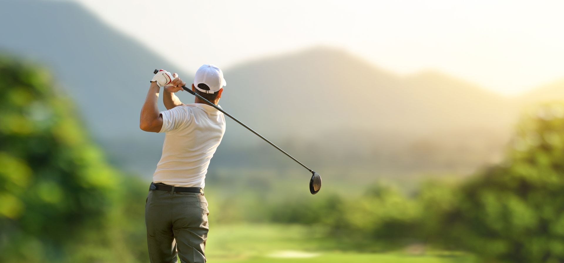A man is swinging a golf club on a golf course.