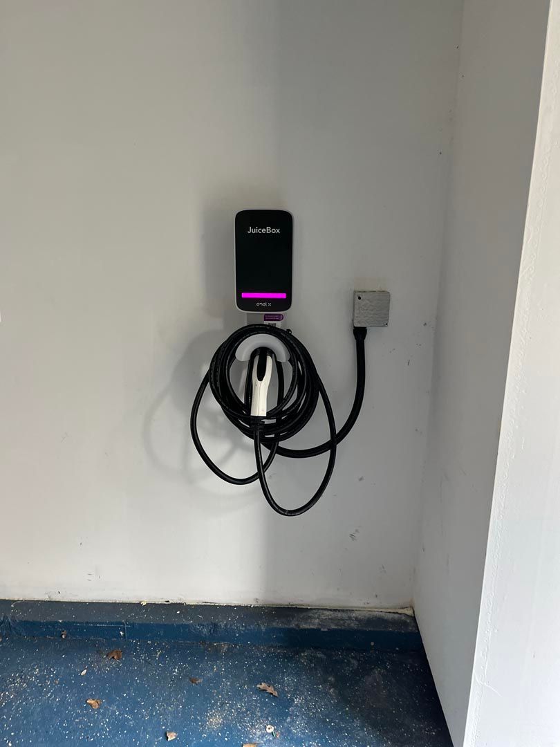 A electric car charger is hanging on a wall in a room.