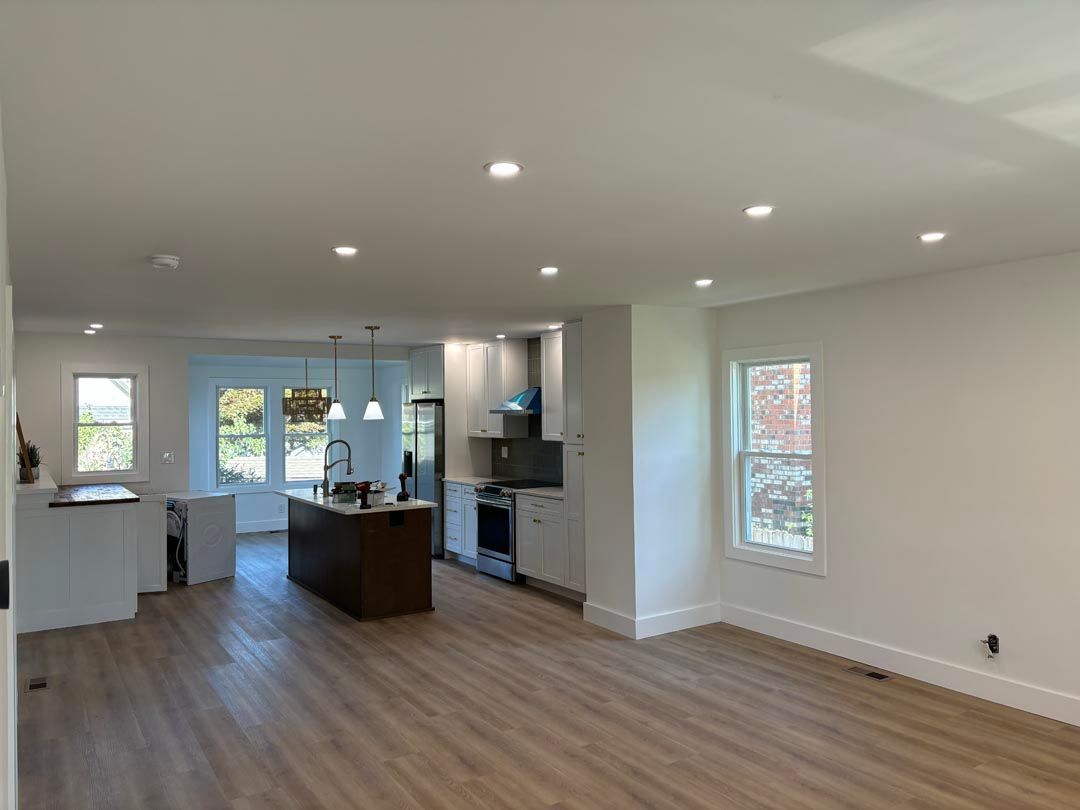 A kitchen and living room in a house with hardwood floors and white walls.