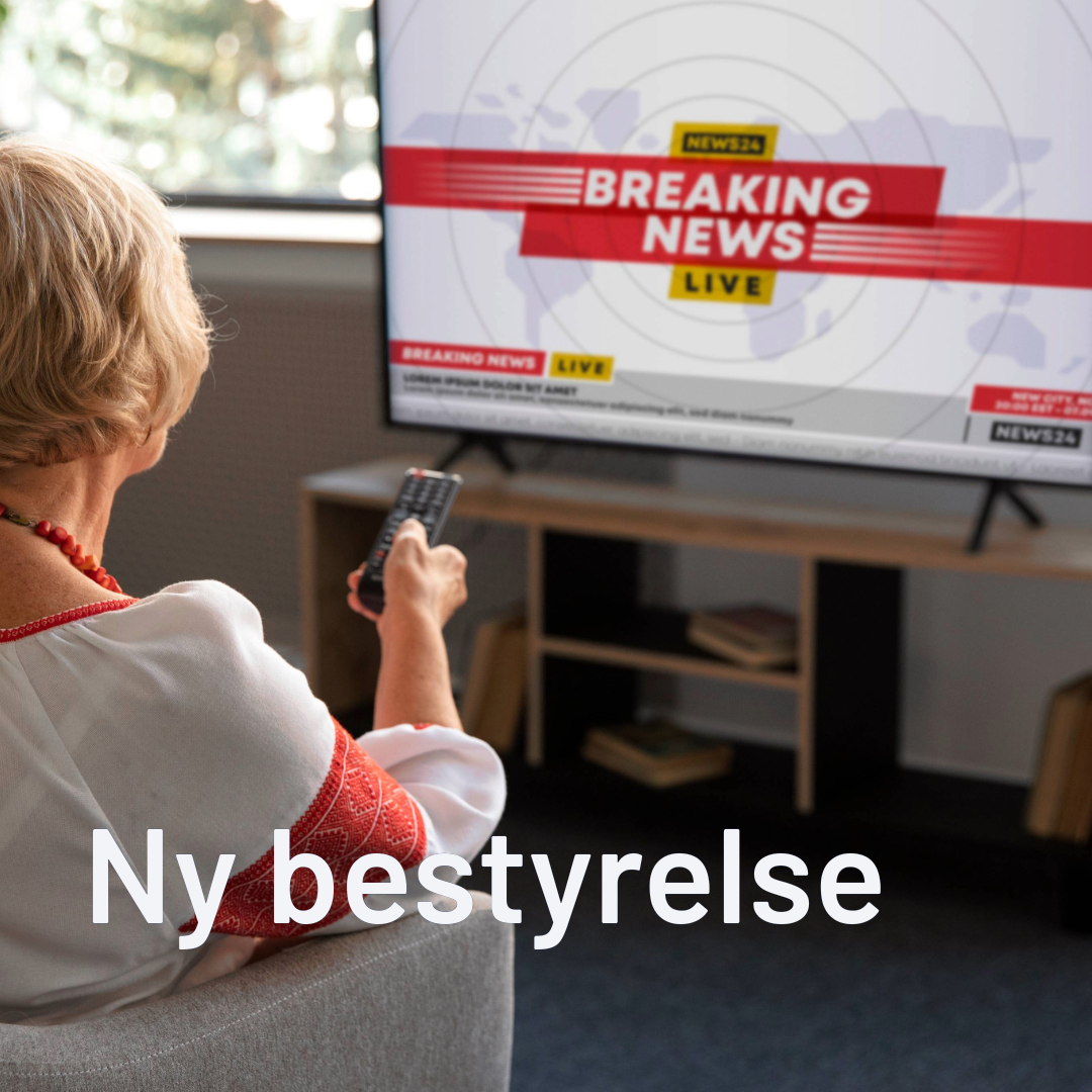 En man der sidder på en blå sofa og har en fjernbetjening i hånden