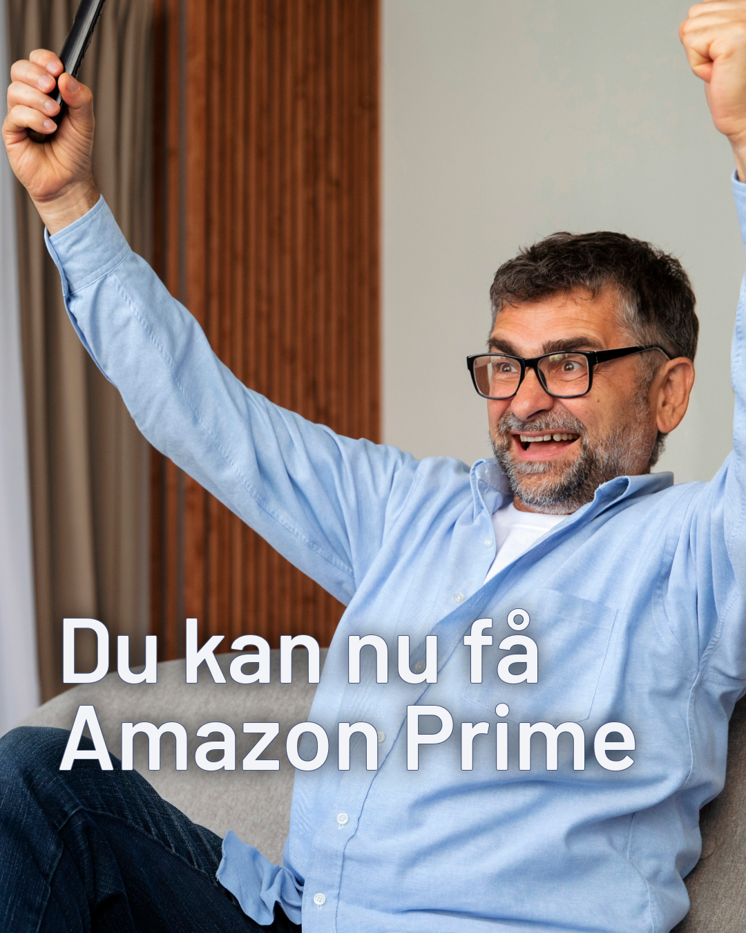En man der sidder på en blå sofa og har en fjernbetjening i hånden