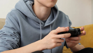 En ung dreng sidder på en sofa og spiller et videospil.