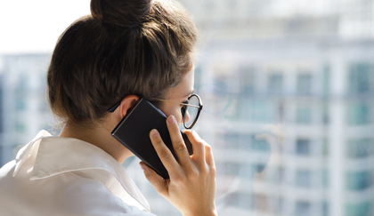Ung kvinde sidder på sofa og kigger på sin mobiltelefon