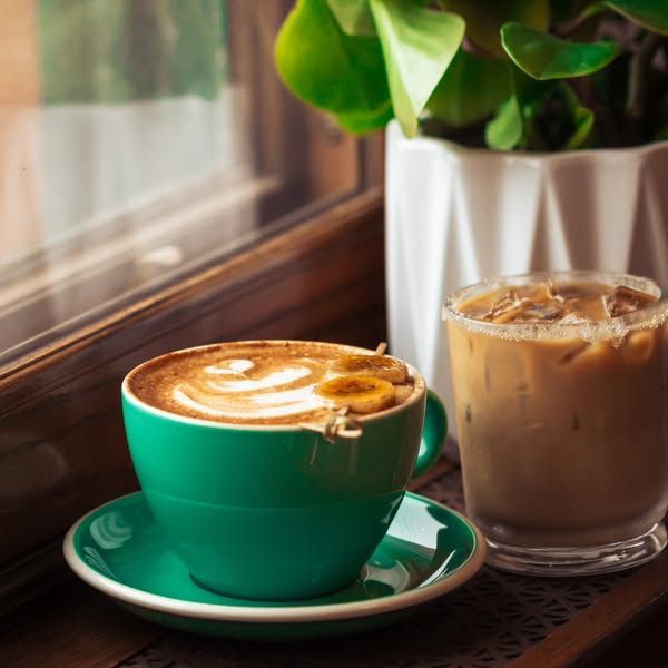 Two cups of coffee on a table next to a window