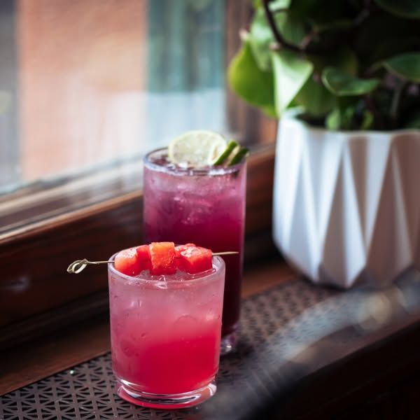 Two drinks are sitting on a table in front of a window.