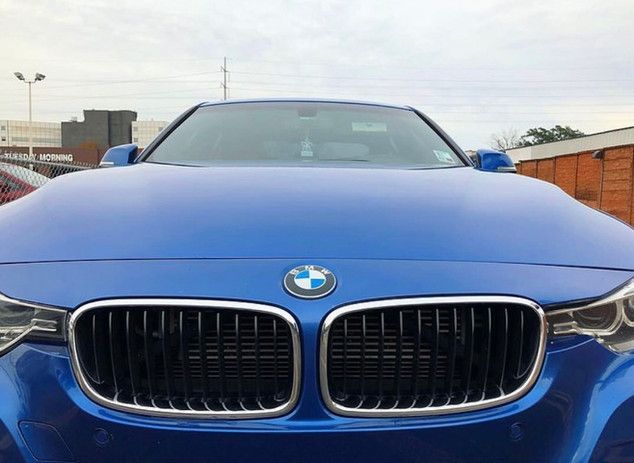 A blue bmw is parked in front of a building.