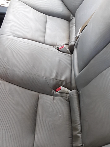 The back seat of a car with a red seat belt.