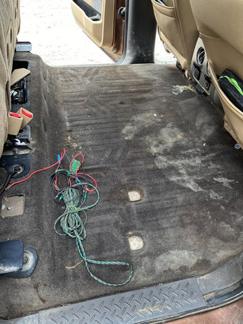 A dirty car floor with a bunch of wires coming out of it.
