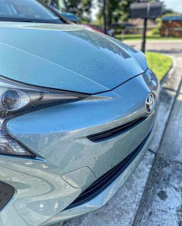 The front end of a toyota prius is parked on the side of the road.
