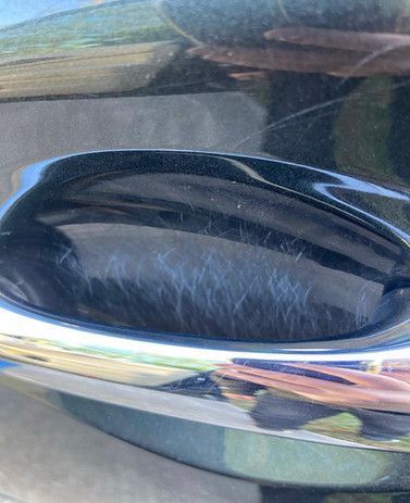 A close up of a car door handle on a black car.