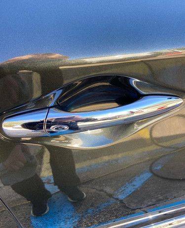 A close up of a car door handle on a black car.