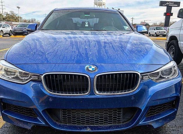 A blue bmw is parked in a parking lot.