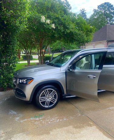 A silver suv is parked in a driveway with its doors open.