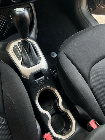 The interior of a jeep renegade with a cup holder and a shifter.