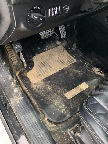 The inside of a dirty car with a dirty floor mat.