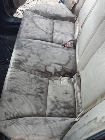 The back seat of a car is very dirty and needs to be cleaned.