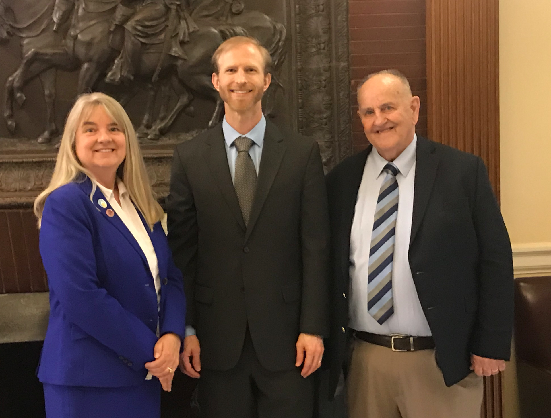 Three people in suits and ties are posing for a picture.