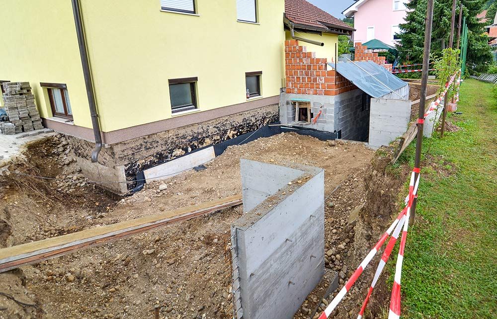 A Yellow House is Being Built Next to a Large Pile of Dirt  — Knobel Builders In Shellharbour, NSW