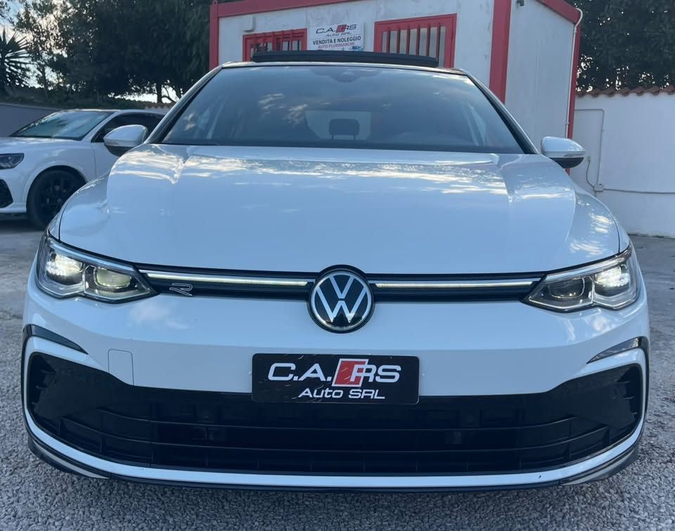 Vista frontale di una Volkswagen bianca parcheggiata davanti a una concessionaria.