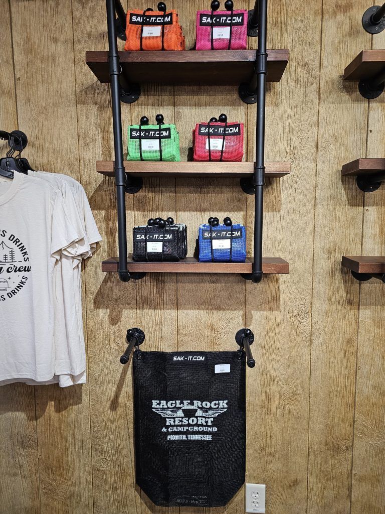 Guitar effect pedals on a wooden shelf, orange, pink, green, blue, and black, beneath a t-shirt and a bag.