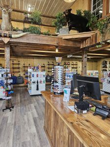 Interior of a store with wooden features and merchandise. A bear and deer mount are visible.
