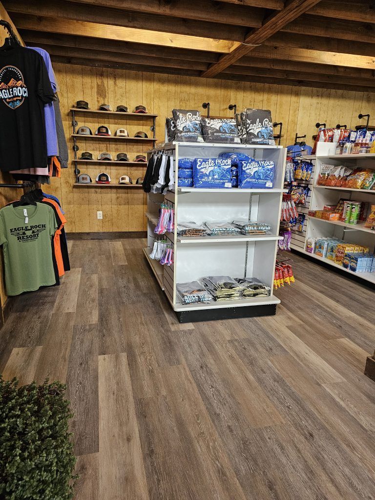 Inside a gift shop with wooden floors and walls; merchandise on shelves, snacks, and t-shirts.