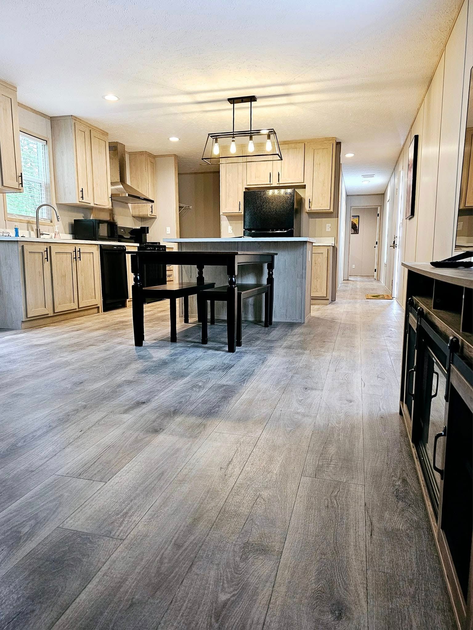 Kitchen with light gray flooring and cabinets, a black table, and a stainless steel appliance.