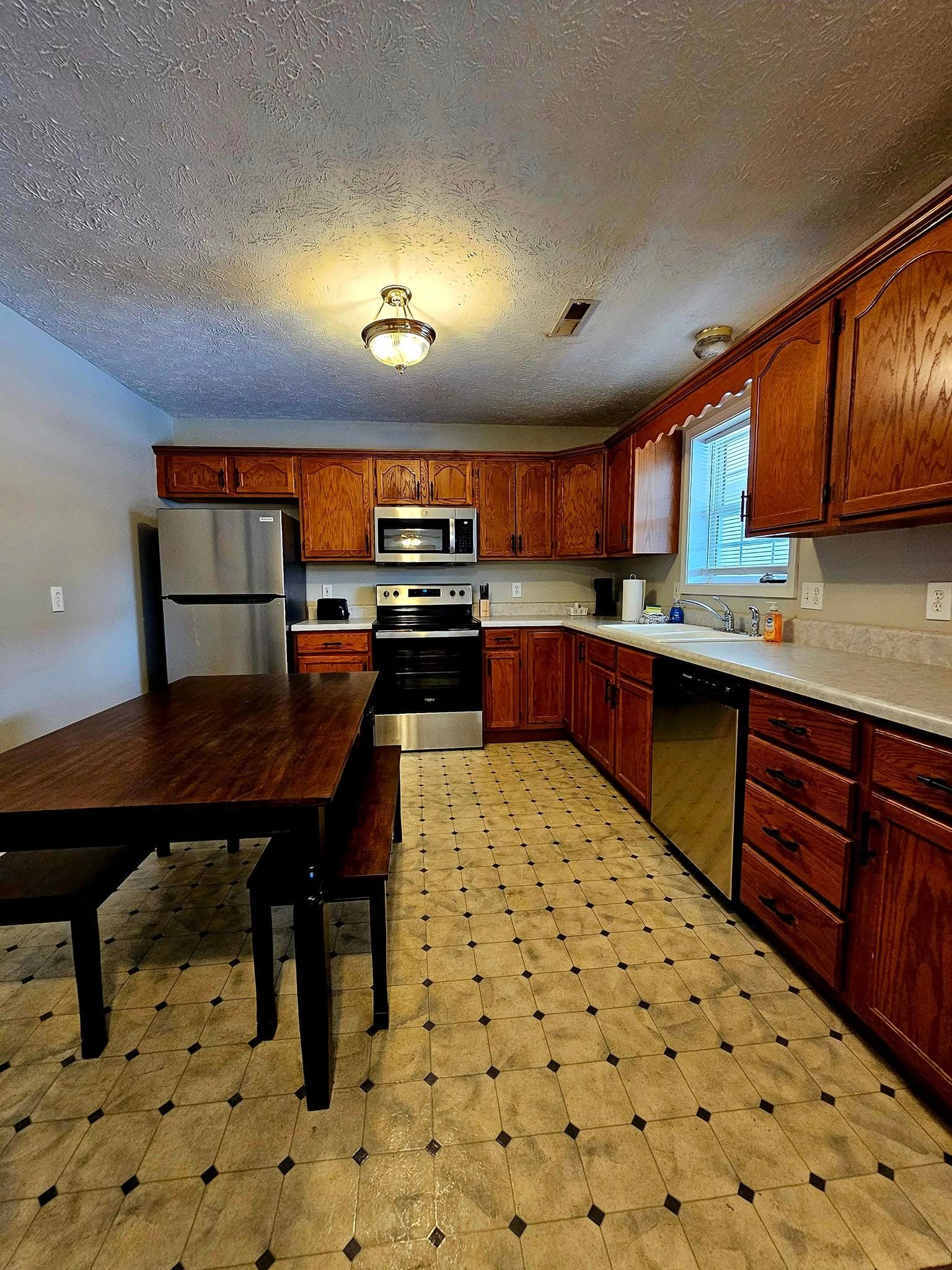Kitchen with wood cabinets, stainless steel appliances, and a table.