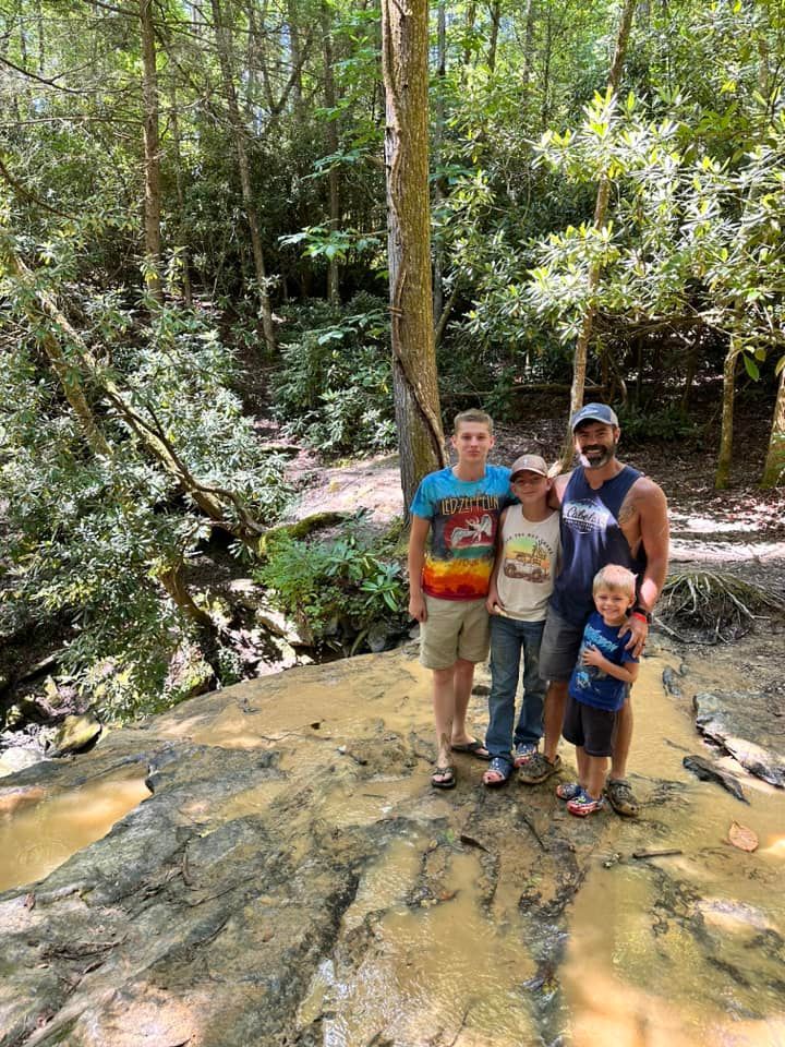 Family of four stands on a rock ledge in a forest.