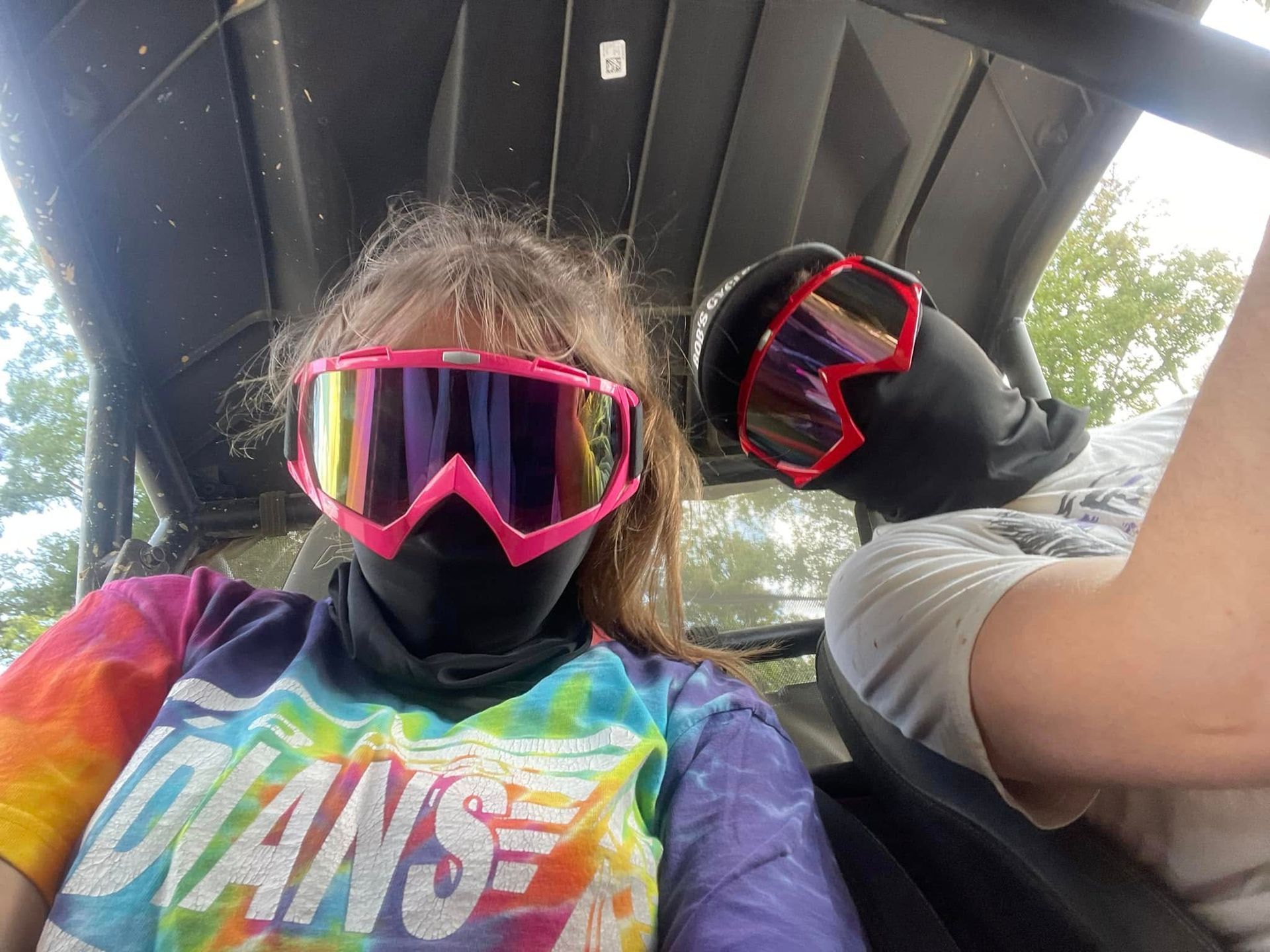 Two people wearing goggles, in an off-road vehicle. 