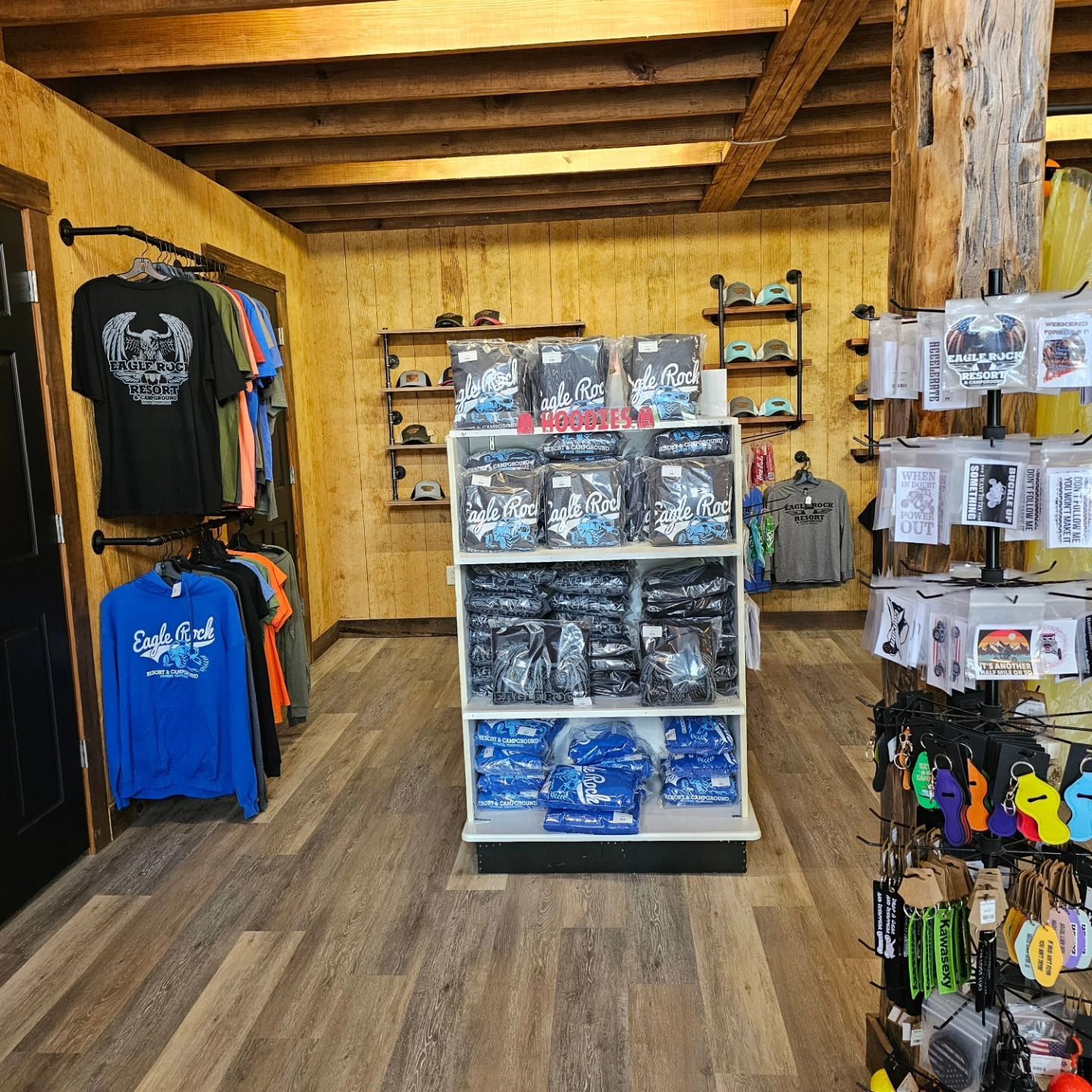 Inside a retail store, displays of shirts and merchandise. Wooden floors and walls with shelves of items.