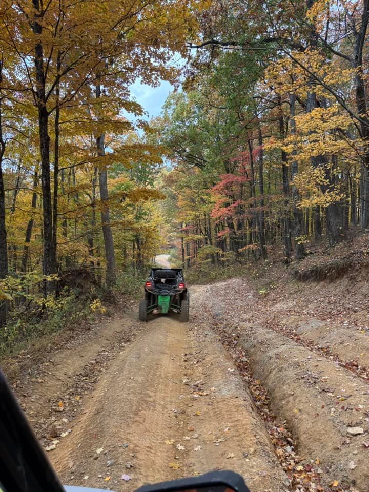 ATV on a dirt road through a colorful autumn forest.