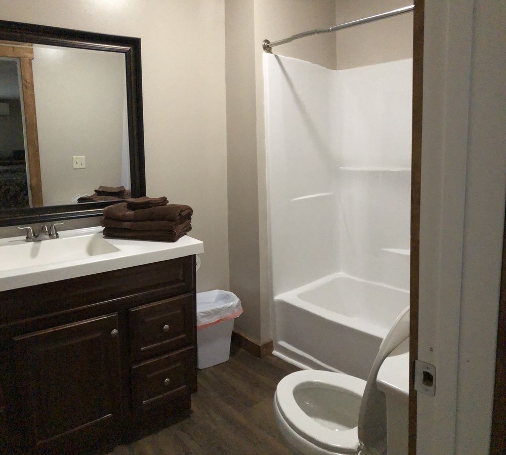 Bathroom with a white tub, dark brown vanity, and a large mirror. Brown towels on the counter.