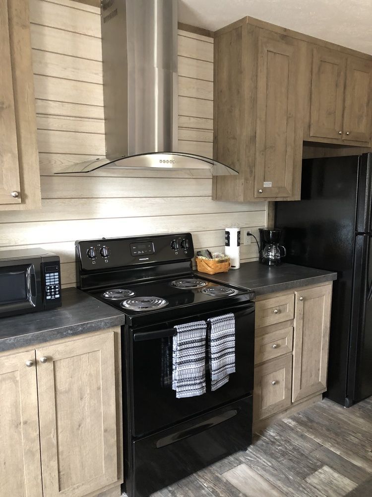 Kitchen with black appliances, light wood cabinets, and gray countertops.