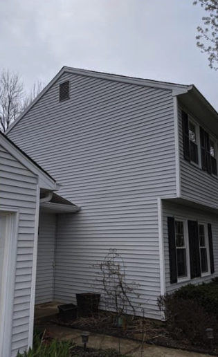 A white house with black shutters is sitting next to a garage.