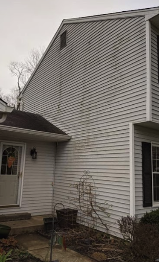 A white house with a black roof and a white siding.