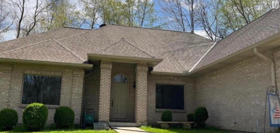 A brick house with a gray roof and a white door is for sale.