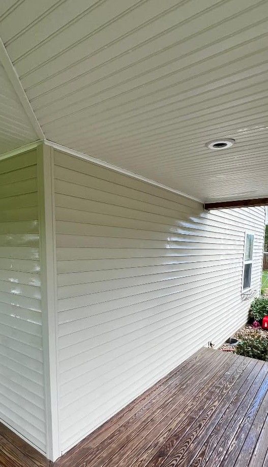 A porch with a white siding and a wooden deck.