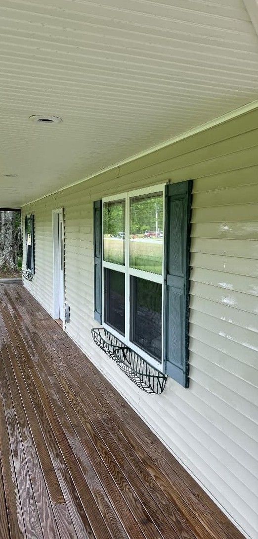 A house with a porch and two windows on the side of it.