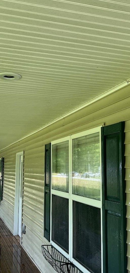 A porch with a screened in window and shutters on a house.