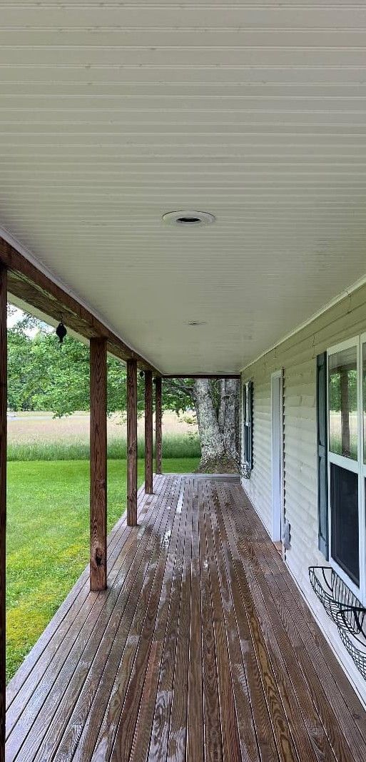 A long porch with a wooden table and a white ceiling.