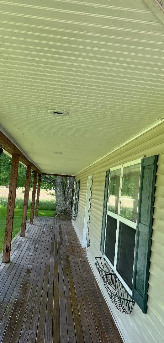A porch with a wooden table and shutters on a house.