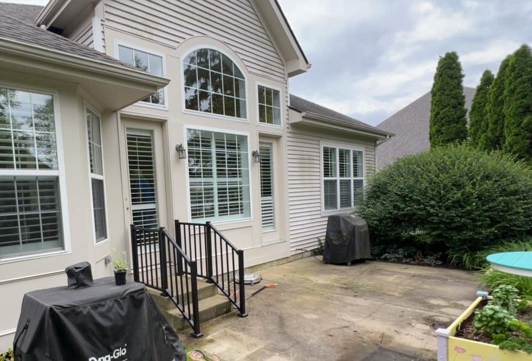 A large white house with a lot of windows and a grill in front of it.