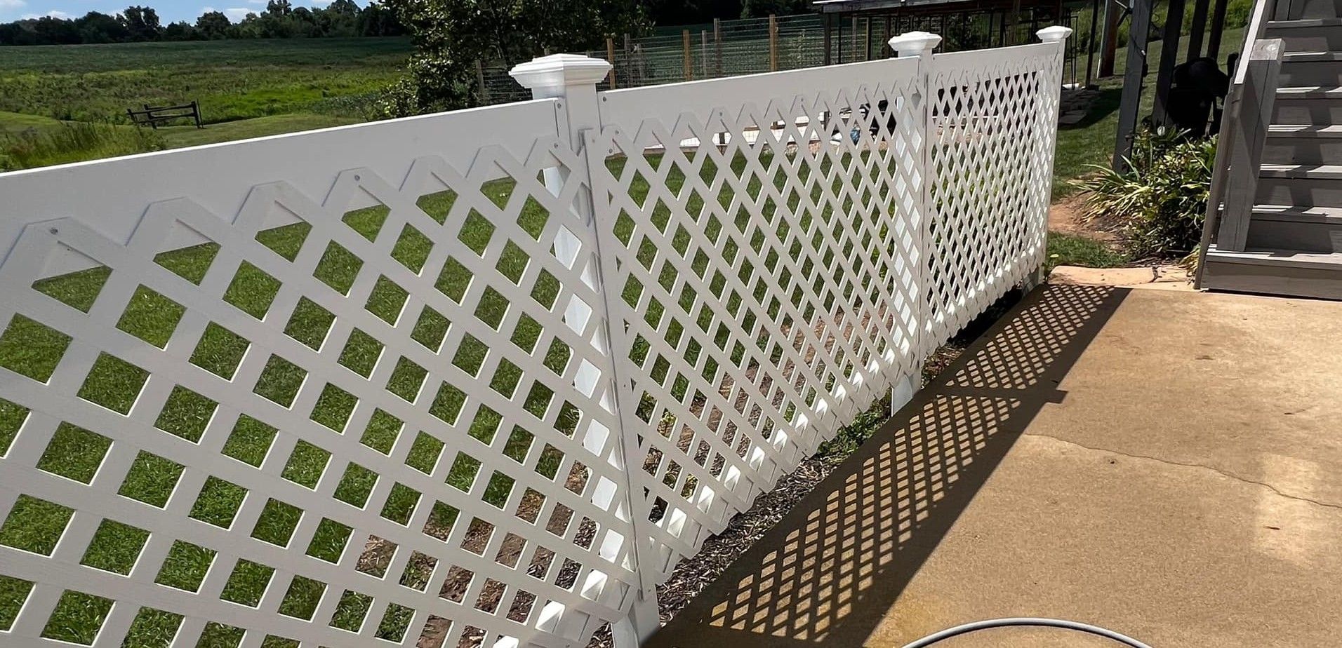 A white lattice fence with a shadow on the ground