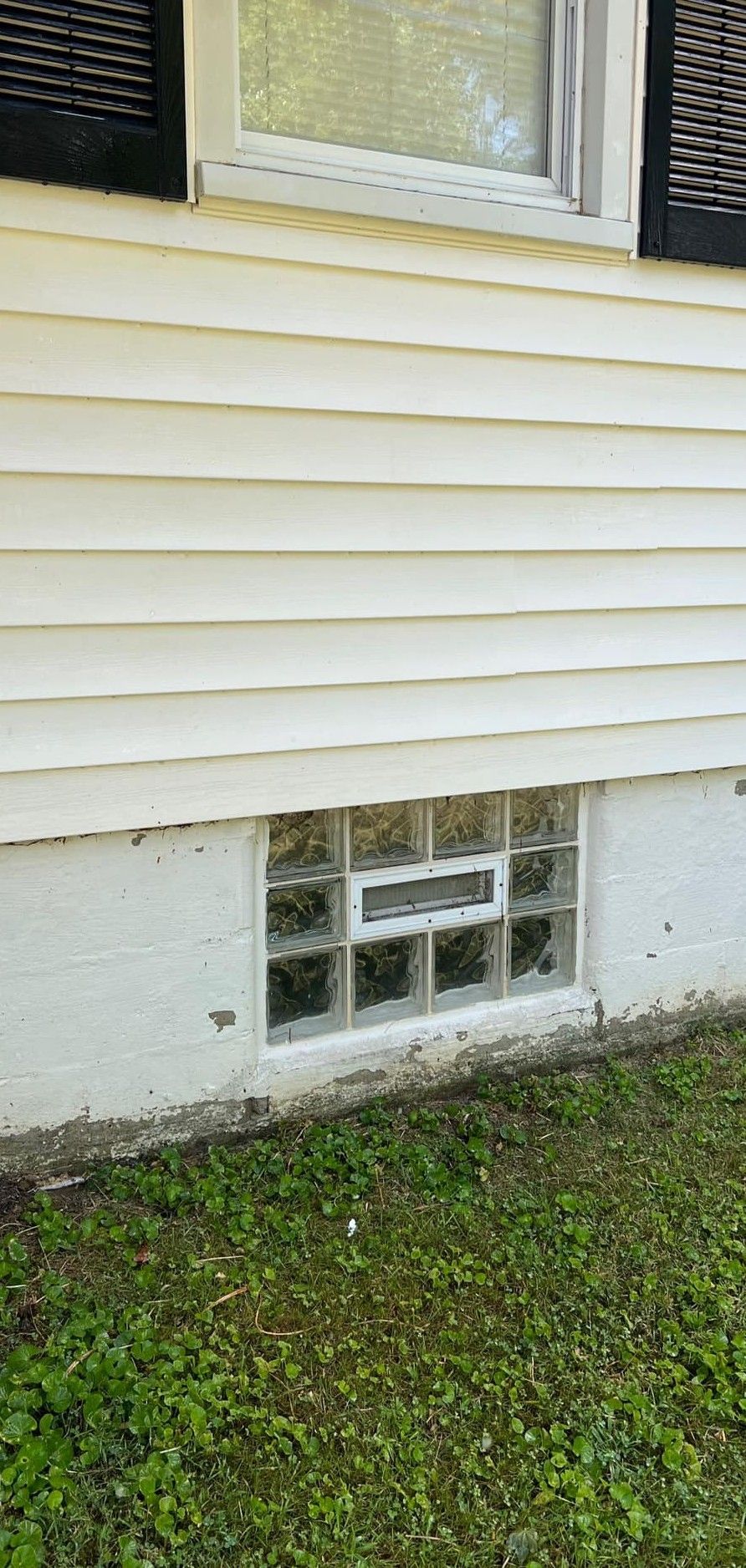 A window on the side of a house with a glass block window.