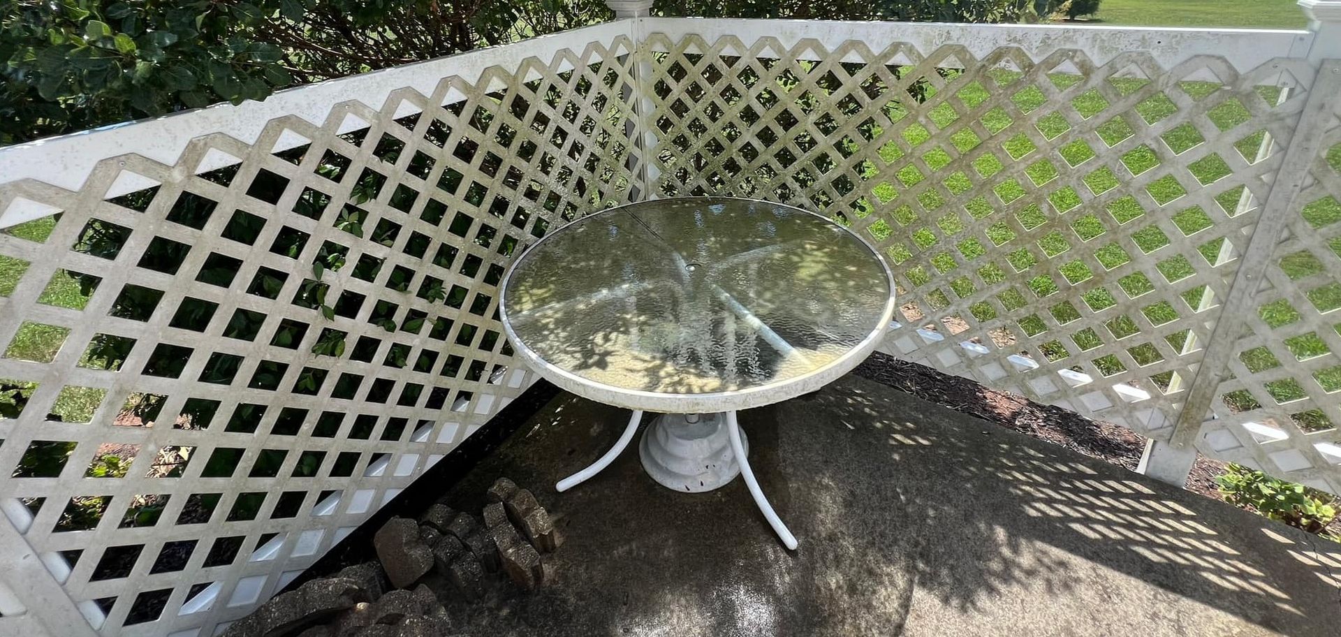 A table and chairs are sitting in front of a white lattice fence.