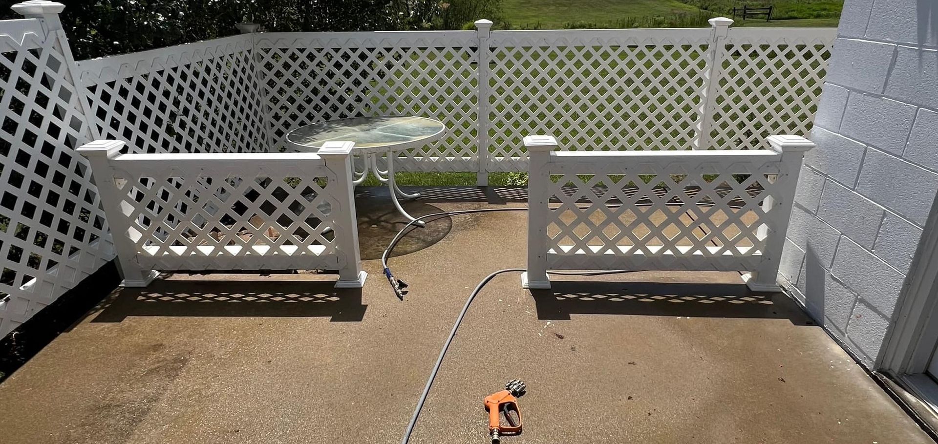 A white lattice fence surrounds a patio with a table and chairs