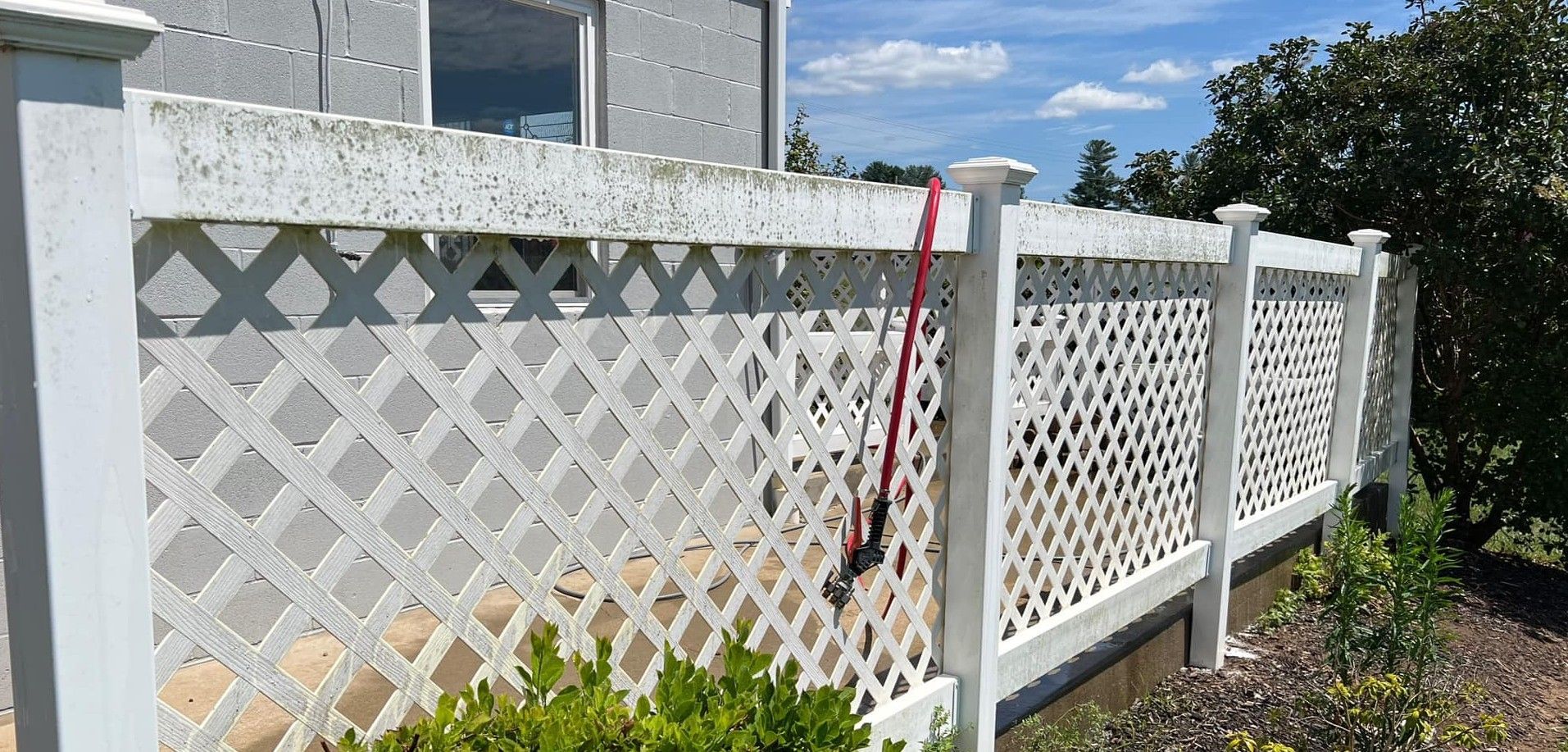 A white lattice fence is sitting in front of a house.