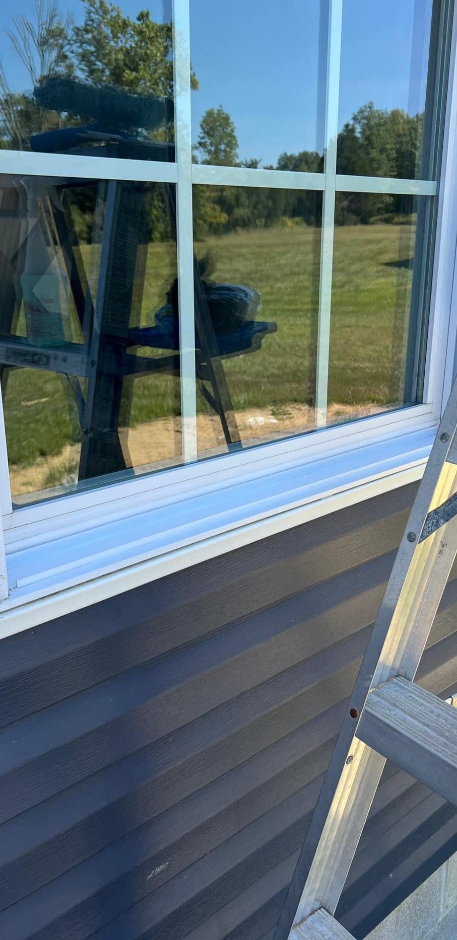 A ladder is sitting next to a window on a house.