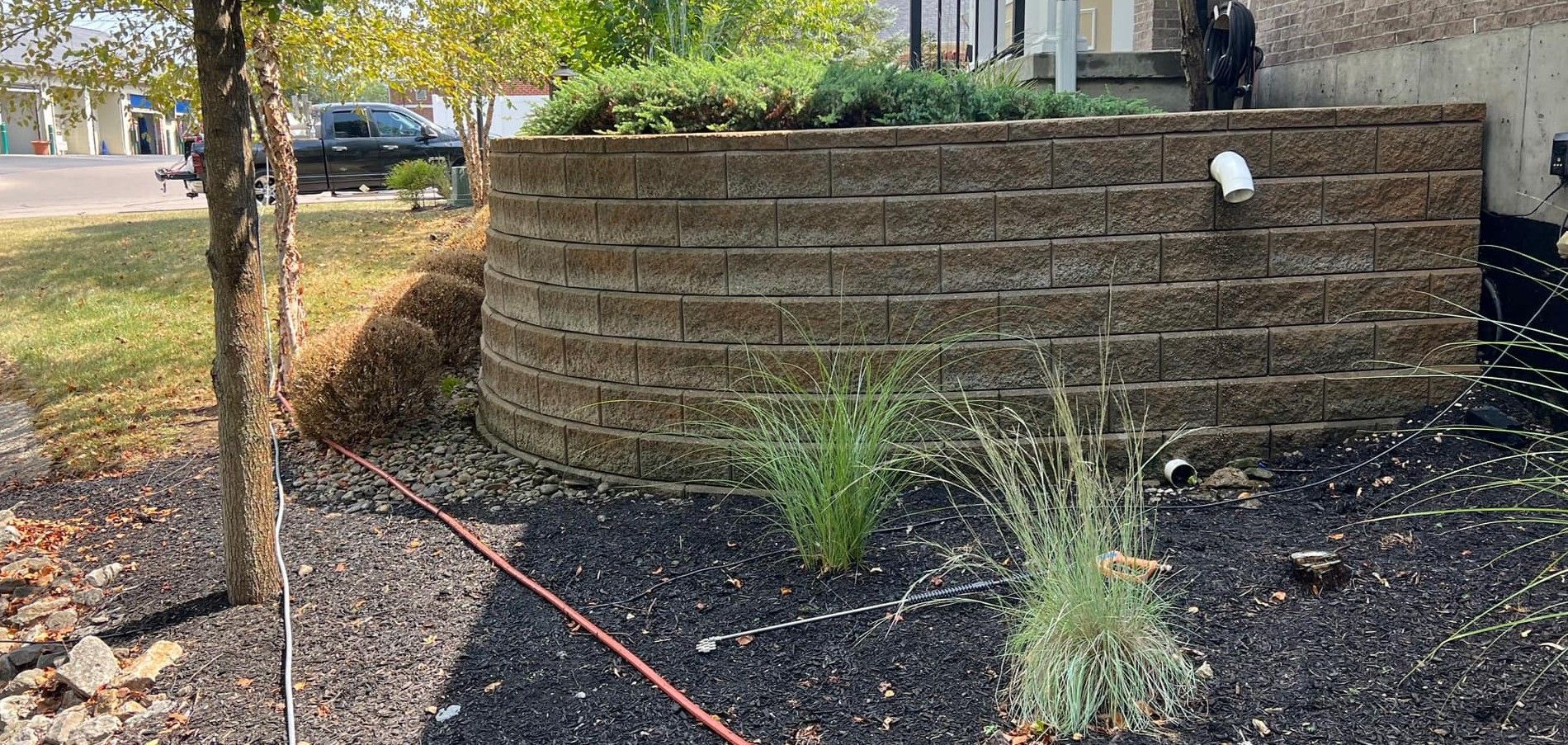 A brick wall with a hose attached to it in front of a house.